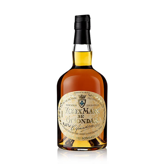  Close-up of Amadieu Vieux Marc de Gigondas Rhône 42% 700 ml, showing the golden color of the grape brandy, elegant bottle design and traditional oak barrel in the background